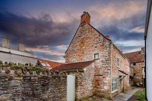 an old stone building with a brick wall at Cottage on Wells High Street in Wells