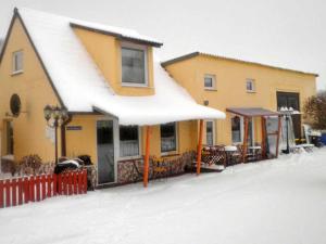 a yellow building with a snow covered roof at Ferienwohnungen in Semlow in Semlow