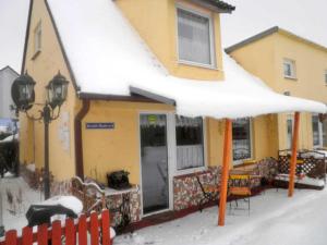a yellow house with an umbrella in the snow at Ferienwohnungen in Semlow in Semlow