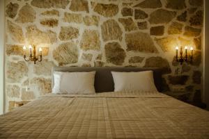 a bedroom with a bed with a stone wall at Sunset Serenity in Himare