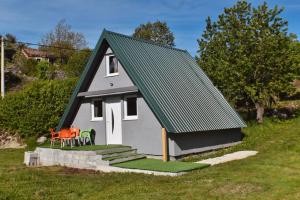 a small house with a green roof and some chairs at Villageescape in Cetinje