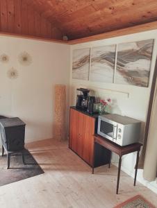 a kitchen with a microwave on a table with a stove at Cozy Cabin near Balka Beach with outdoor toilet and kitchen in Neksø