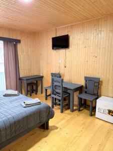 a bedroom with tables and chairs and a bed and a television at Садиба ВидНа in Kvasy