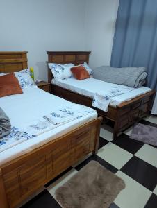 two twin beds in a room with a checkered floor at Eden Vista Stays in Dar es Salaam