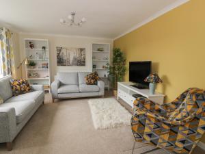 a living room with a couch and a tv at The Rowans in Newton Stewart