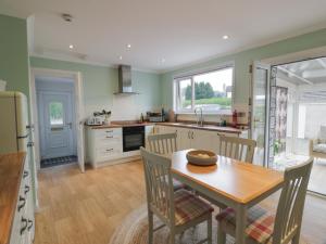 a kitchen with a wooden table and a dining room at The Rowans in Newton Stewart