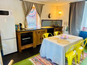 a kitchen with a table with yellow chairs and a white refrigerator at La MaisonneTTe d'ElodibiZa ! in Moret-sur-Loing +11 photos