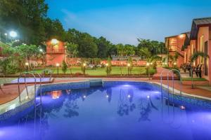 a large swimming pool in a yard at night at Earavat Resort in Rāmnagar