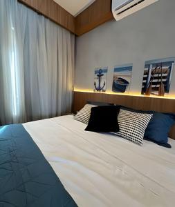 a bedroom with a large white bed with blue pillows at Petit da Pipa Studios Privados in Pipa