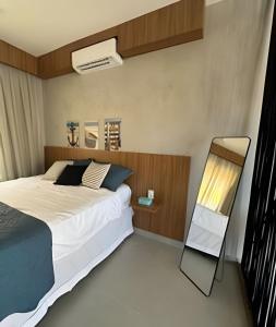 a bedroom with a large bed and a mirror at Petit da Pipa Studios Privados in Pipa