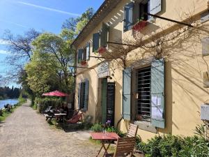 a building with a table and chairs next to a river at Cabane Le Nid - CANAL DU MIDI in Carcassonne