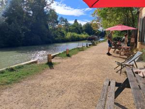 a man standing under an umbrella next to a river at Cabane Le Nid - CANAL DU MIDI in Carcassonne