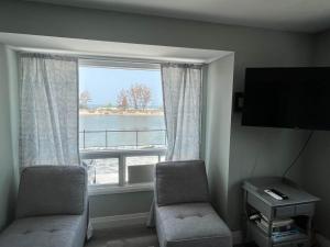 a room with two chairs and a large window at Riverside Haven on Georgian Bay in Wasaga Beach +5 photos