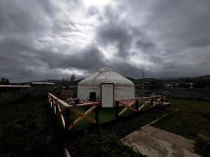 a yurt in a field under a cloudy sky at Aruna Guesthouse in Saty