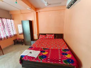 a bedroom with a bed with a red comforter at Hotel Rajlaxmi in Neil Island