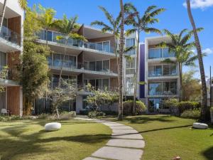 an apartment building with palm trees and a walkway at 3BR Beachfront Private Pool Ultravioleta Cabarete in Cabarete