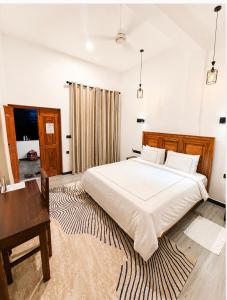 a bedroom with a large white bed and a desk at Swiss Bay Hotel & Resort-Arugambay in Pottuvil