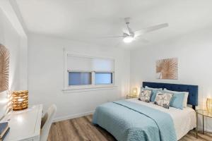 a white bedroom with a blue bed and a window at Bright 2BR Oceanview Condo in Key West