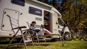 a woman sitting in a chair in front of a rv at Blue Mist Motel Florence in Florence