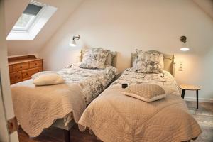 two beds in a bedroom with a window at Ker Adèle, longère cosy au cœur d'un bois in Ploërdut