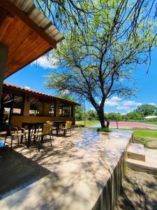 a patio with a table and chairs under a tree at Posada La Ernestina Villa de las rosas in Villa Las Rosas