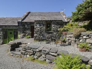 a stone cottage with a table and chairs in front of it at Beudy Bach in Llanbedr