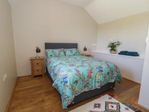 a bedroom with a bed with a floral bedspread and a window at Beudy Bach in Llanbedr