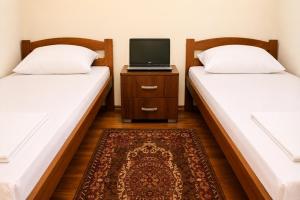 two beds in a room with a laptop on a night stand at Balkan House in Mostar