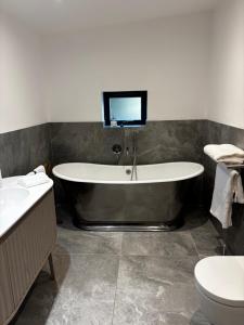a bathroom with a tub and a toilet and a tv at Barnfield house in Upham