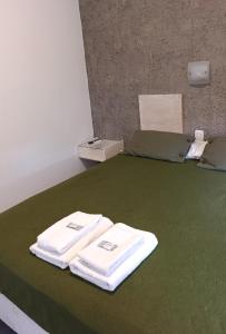 two towels are sitting on a green bed at Hotel Cafayate Design in Cafayate
