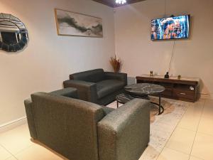 a living room with a couch and a chair and a table at Le Cape Nest Guest House in Parow +6 photos