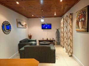 a living room with two chairs and a tv at Le Cape Nest Guest House in Parow