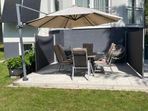 a patio with a table and chairs under an umbrella at Ferienwohnung Moor in Wickede (Ruhr)