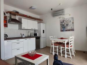 a kitchen with white cabinets and a table and chairs at Apartman Leana in Krk