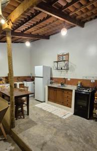 a kitchen with a table and a white refrigerator at Estúdio aconchegante com cozinha externa e quintal in Morro do Chapéu