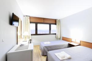 a hotel room with two beds and a television at São Roque Suites in Bragança