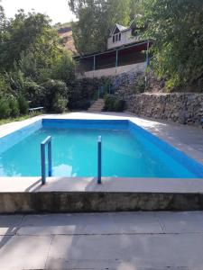 a large blue swimming pool with a house in the background at Адами драхт in Garni +11 photos