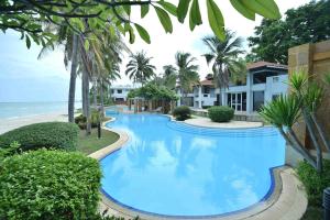 a large blue swimming pool next to a beach at Dar's Haven Cha-Am in Cha Am