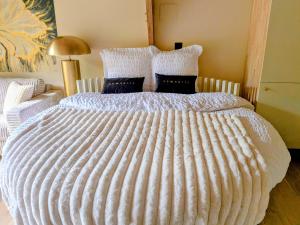 a bed with a large white comforter on it at Domaine du Bois l'Abbé - Le Nid in Saint-Martin-Boulogne