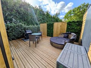 a wooden deck with a grill and a table and chairs at Domaine du Bois l'Abbé - Le Nid in Saint-Martin-Boulogne