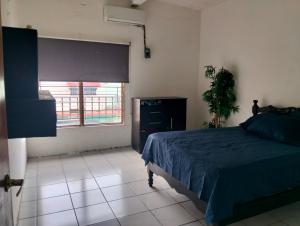 a bedroom with a blue bed and a window at Tu hogar en tapachula in La Concepción