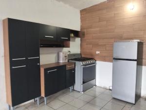 a kitchen with black cabinets and a white refrigerator at Tu hogar en tapachula in La Concepción