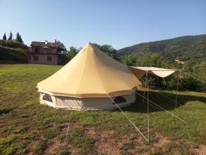 a tent in a field with a house in the background at El Astial De Ezquerra - Camp in Ezquerra