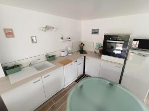 a kitchen with white cabinets and a sink and a refrigerator at Le nid des mésanges in Veigné +3 photos