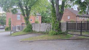 a fence in front of a house with a tree at Zak Air B&B Stay 9 people's in Birmingham