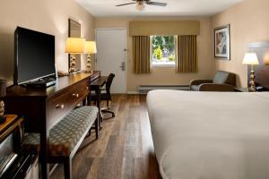 a hotel room with a bed and a desk with a television at Scottish Fairway Inn in Monterey
