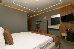 a bedroom with a large white bed and a flat screen tv at DejaVu Hotel in Prizren