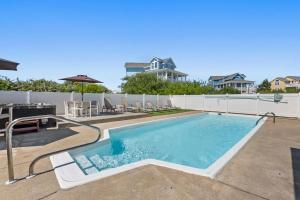 a pool with chairs and a table and a house at Anchors Away in Corolla