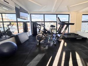 a gym with two exercise bikes in a room with windows at Suporte VIP: TOPstudio no Centro c/Piscina Jacuzzi in Poços de Caldas