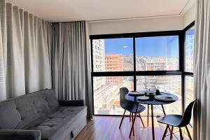 a living room with a couch and a table with chairs at Suporte VIP: TOPstudio no Centro c/Piscina Jacuzzi in Poços de Caldas